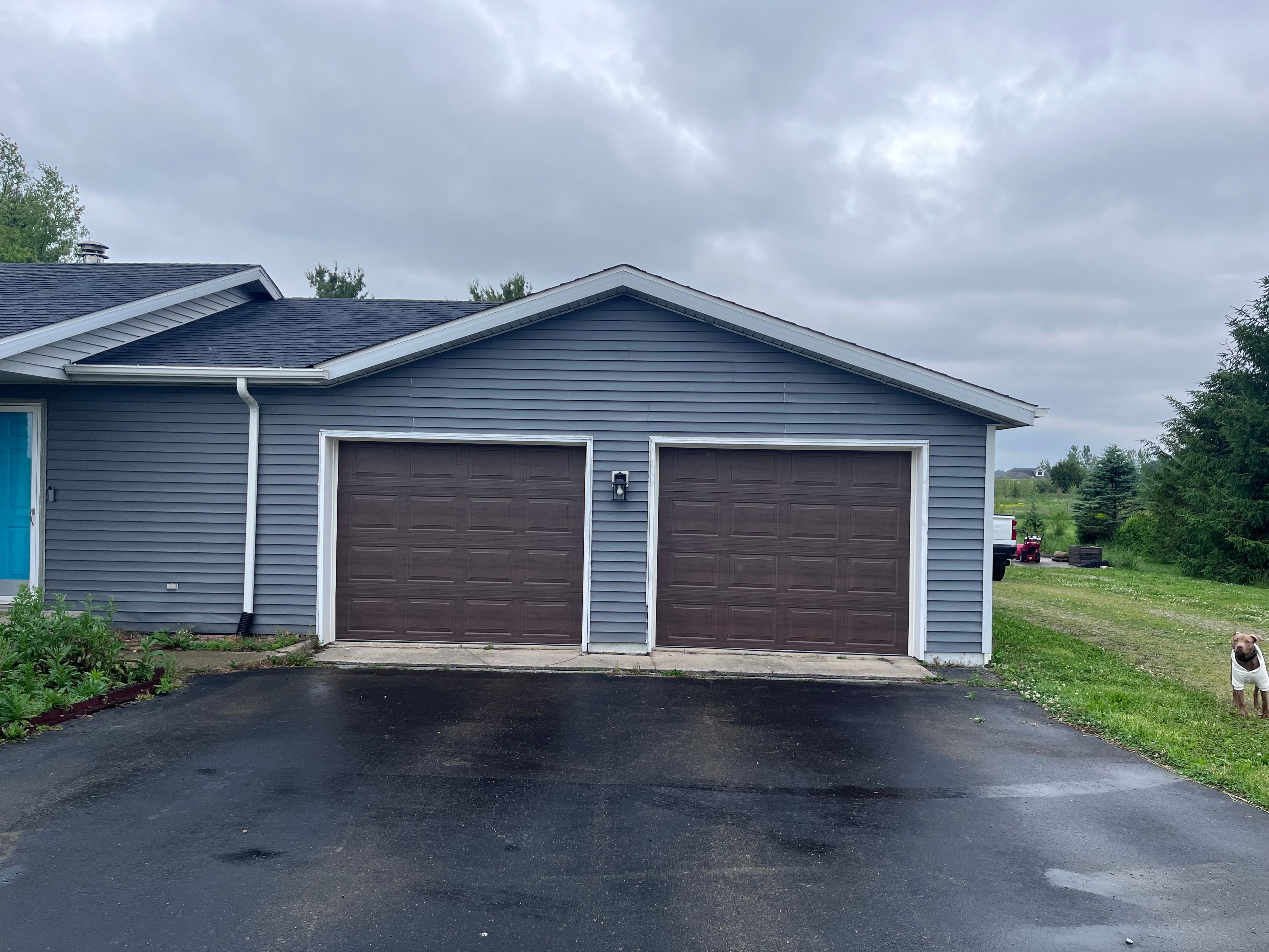 Residential garage after RADCO installation — new brown wood-grain doors on blue house
