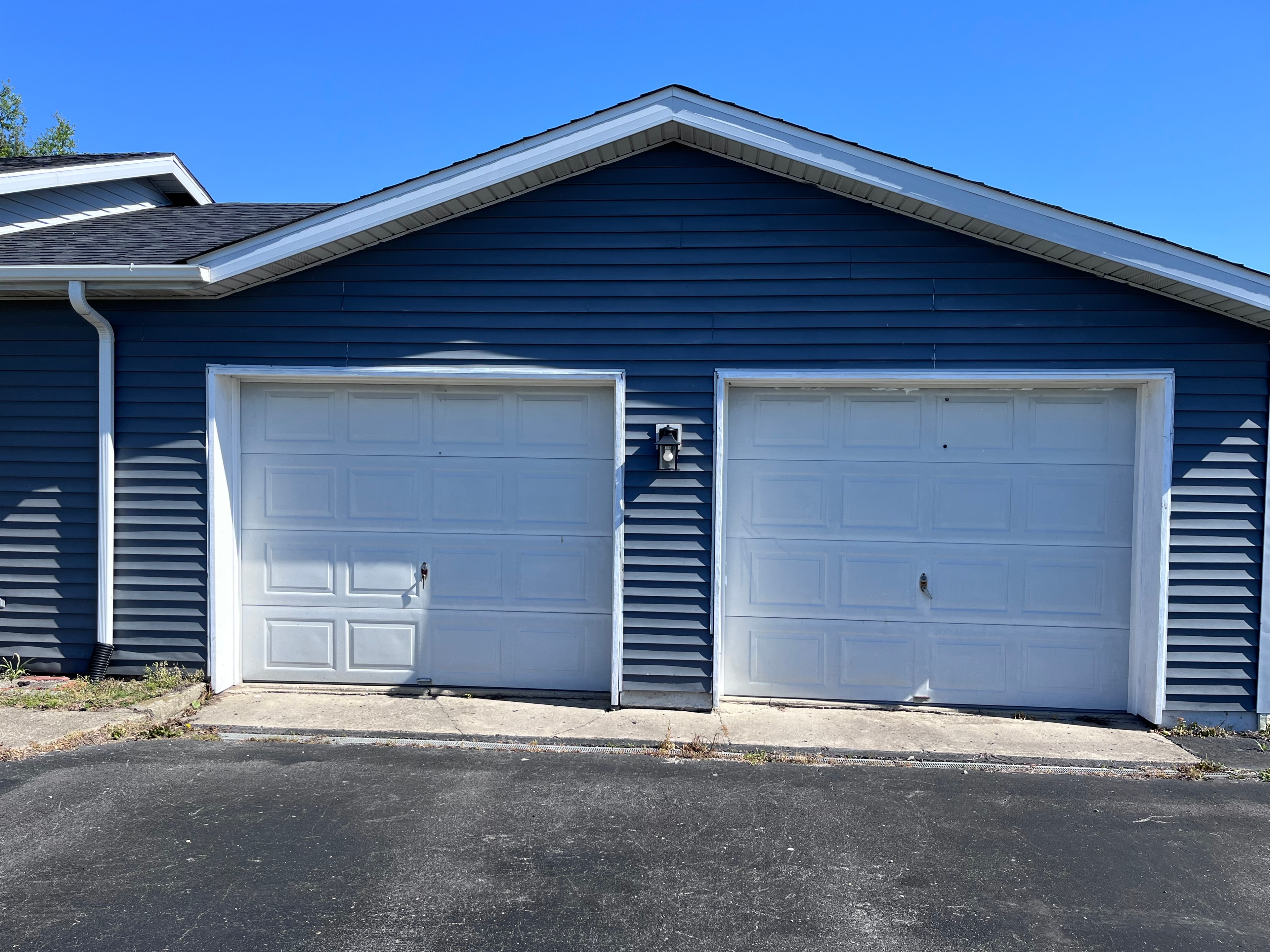 Residential garage before RADCO installation — original white doors on blue house