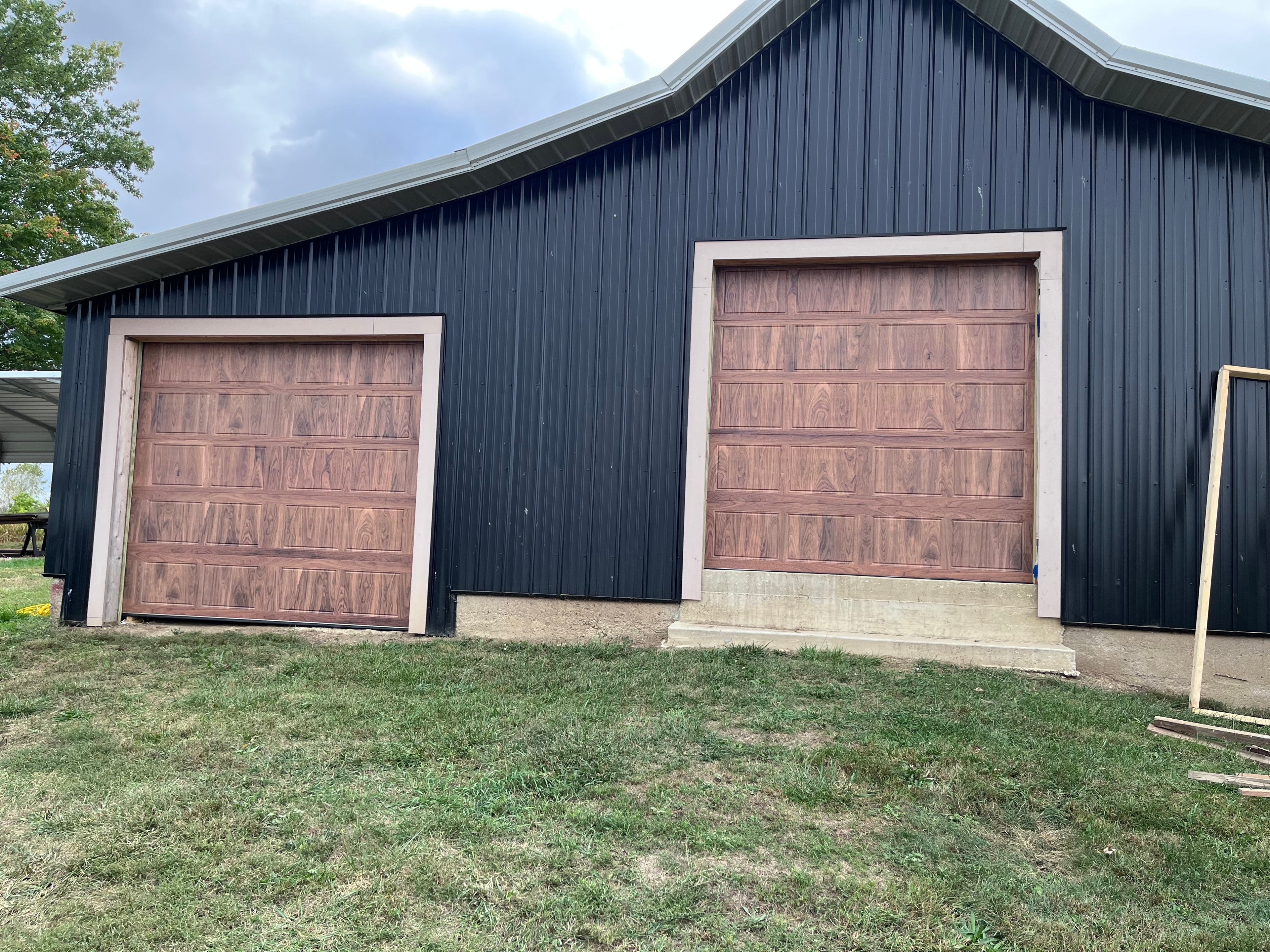 Completed barn garage door installation — two wood-grain overhead doors on steel building